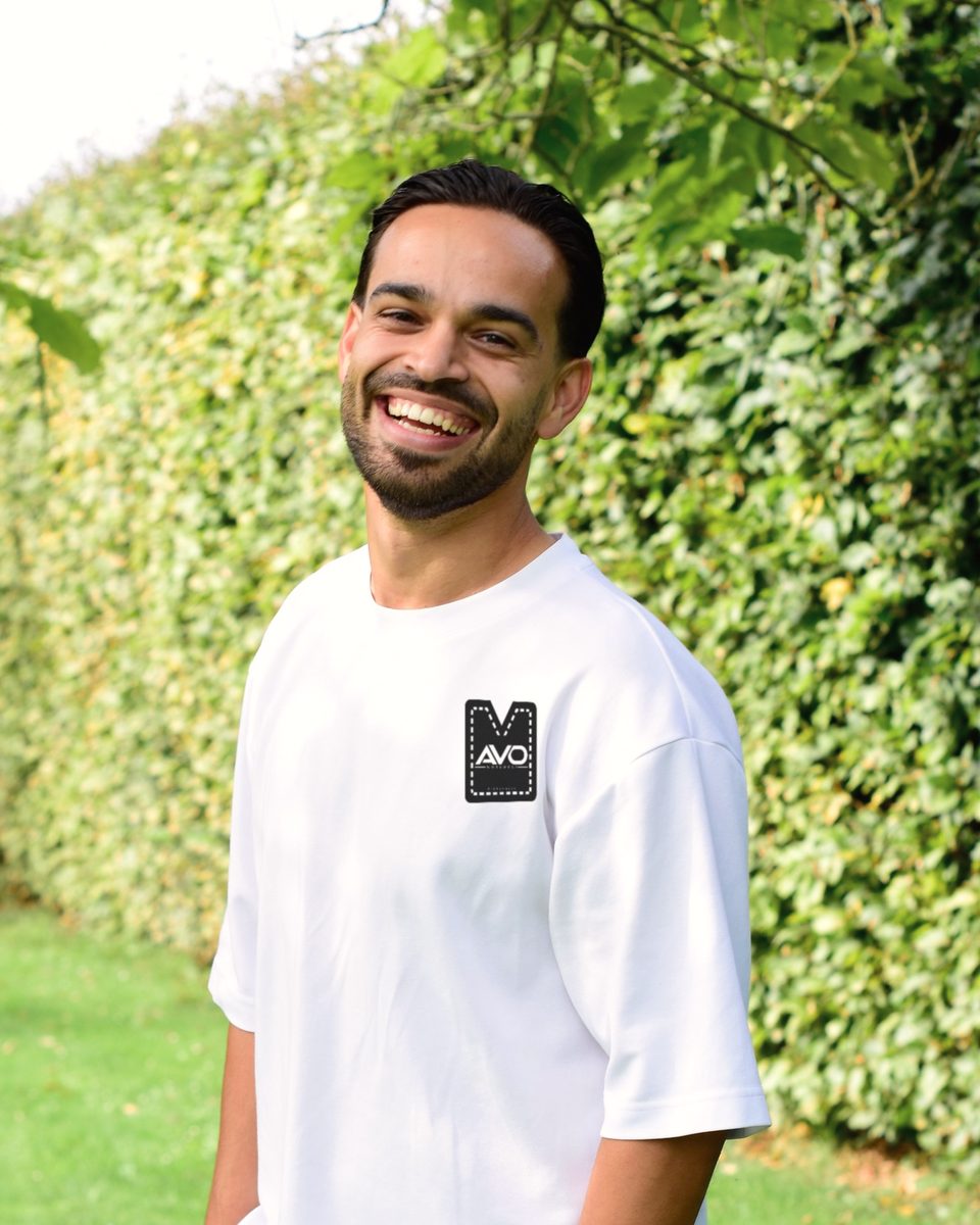 Alex van Overdijk, eigenaar van AVO Workwear, lachend in een wit T-shirt met het logo op de borst