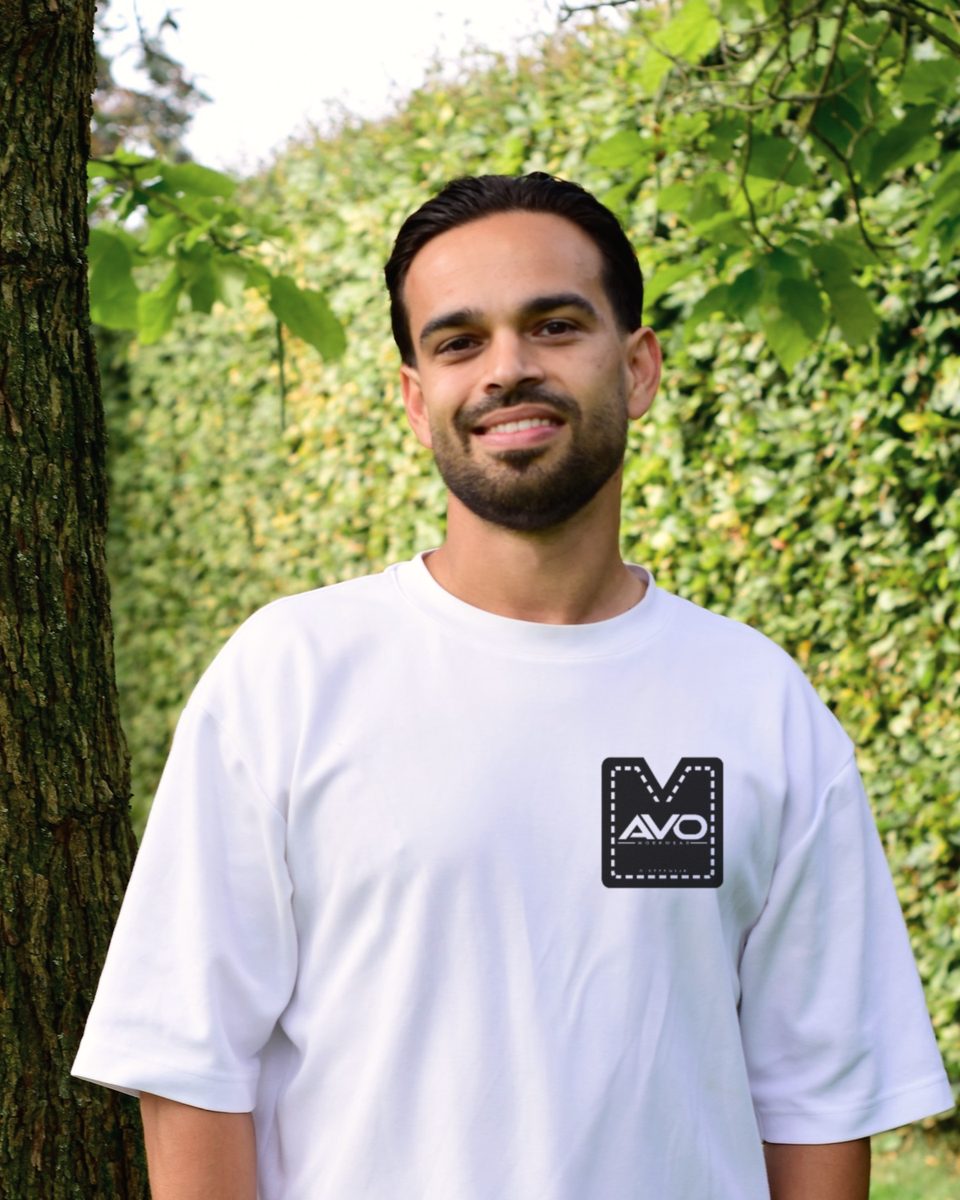 Alex van Overdijk glimlacht in een wit T-shirt met het AVO Workwear-logo